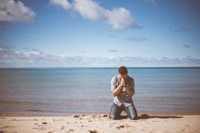Man praying on beach
