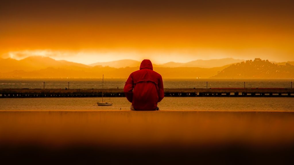 Person staring into sunset wearing red