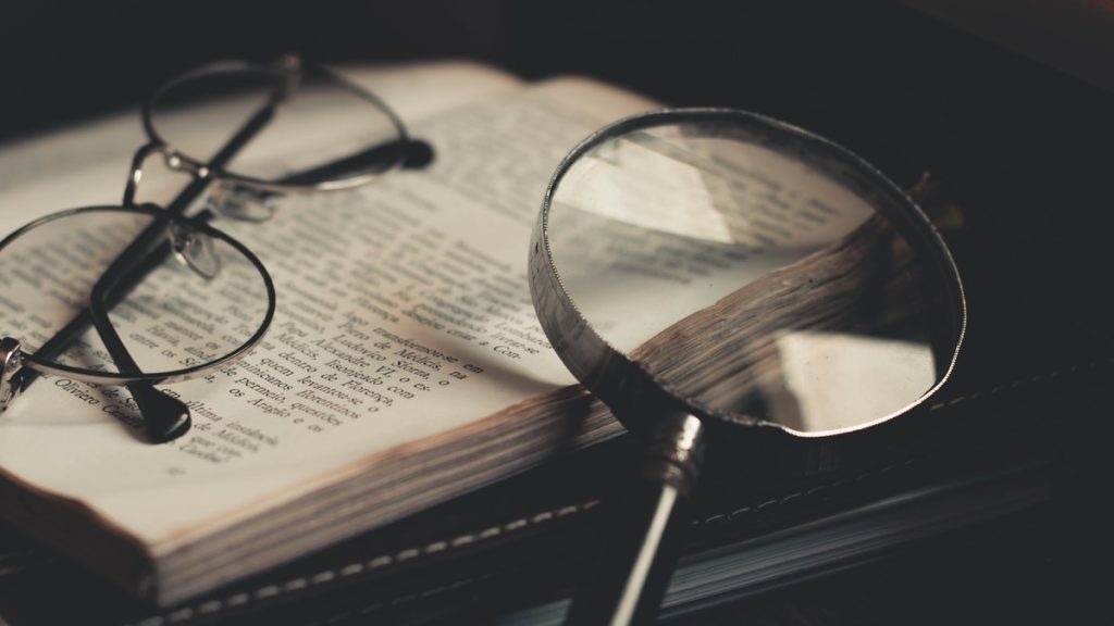 Magnifying glass and glasses on open book