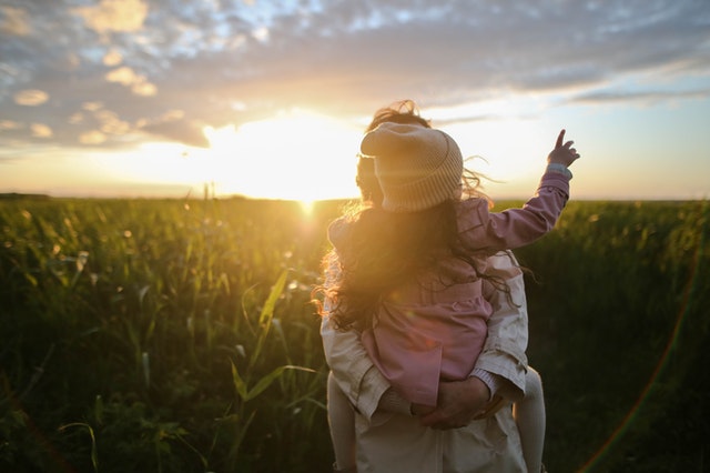 Woman holding little girl in field of happiness